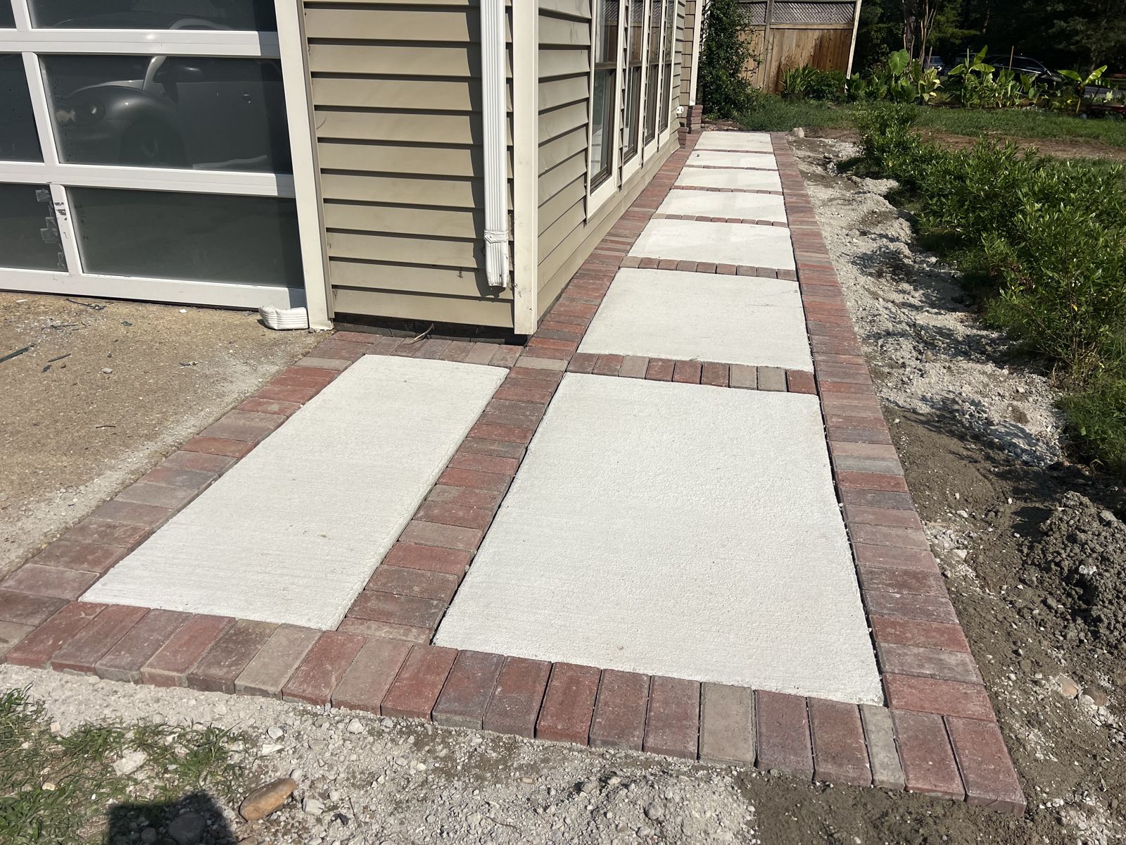 Concrete sidewalk framed with a red brick paver border in Virginia Beach