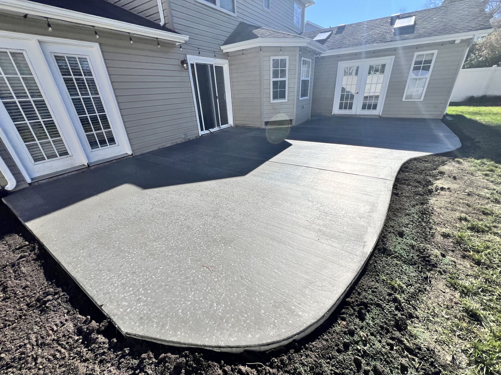 Curved concrete patio extension flowing around a Virginia Beach home